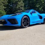 Blue sports car parked in sunny area.