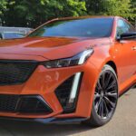 Orange car parked in sunny area.