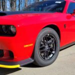 Red sports car parked on concrete driveway.