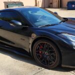 Black sports car parked in a lot.