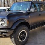 Black off-road SUV parked near trees.