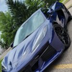 Blue sports car parked on asphalt road.